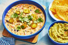 two bowls of guacamole and tortilla chips on a blue cloth