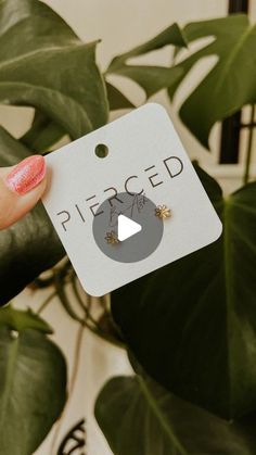 a person holding up a piece of paper with the word pierced on it in front of a plant