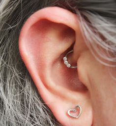 a woman's ear with a heart shaped nose ring