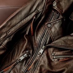 a brown leather jacket sitting on top of a chair