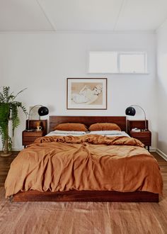 a large bed sitting next to a window in a room with wooden floors and walls