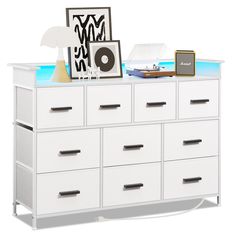 a white dresser with many drawers and pictures on it's top shelf, against a white background