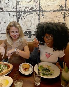 two women sitting at a table eating pizza