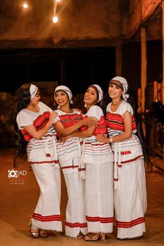 four women in white and red dresses standing together