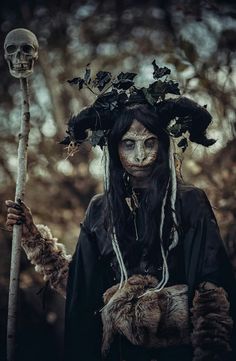 a woman dressed as a skeleton holding a stick and wearing a wreath on her head