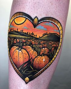 a heart shaped tattoo with pumpkins in the field and sunset on it's side