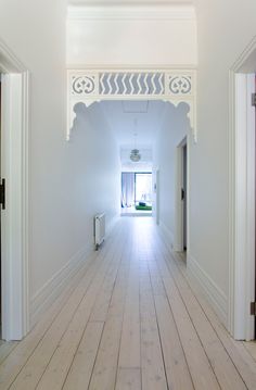 an empty hallway with white walls and wood floors