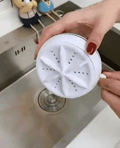 a woman is holding a strainer in her hand over a kitchen sink faucet