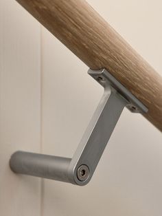 a close up of a wooden pole with a metal handle on the end and a white wall in the background