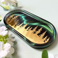 a green and gold tray sitting on top of a table with white flowers around it