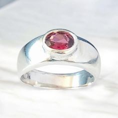 A heavy, chunky 6g silver ring in Medieval and Celtic style with beautiful red garnet. The rhodilite garnet is bezel set into the silver in a flush style for easy, everyday wear. You're a laid back, relaxed individual who loves a modern twist on the solid,  quality jewellery of Medieval and Celtic styles.  This ring has a real quality feel to it and the garnet really sparkles on your finger. The silver is high quality recycled  silver from a highly reputable UK supplier and the garnet was source Modern Garnet Rings For Anniversary, Gemstone Dome Ring With Round Band For Gift, Gemstone Dome Ring With Round Band As Gift, Modern Silver Rings With Ruby, Gemstone Dome Ring As Gift, Dome Ring With Gemstone As Gift, Modern Silver Ruby Rings, Silver Ruby Ring With Gemstone, Silver Ruby Ring With Gemstone In Round Band