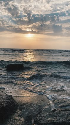 the sun is setting over the ocean with waves