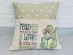 a pillow that has a dinosaur reading a book on it, with the words read me now