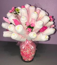 a vase filled with pink and white flowers on top of a table next to a purple wall