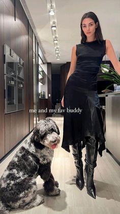 a woman standing next to a dog in a kitchen