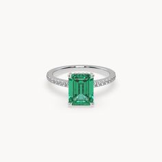 an emerald and diamond ring on a white background