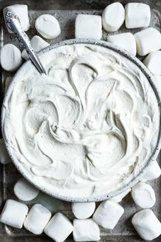 a bowl filled with white marshmallows on top of a metal tray next to a spoon