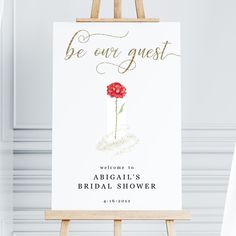 an easel with a sign on it that says be ever guest, and a red flower