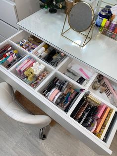 a white desk with lots of different items in it and a mirror on the wall