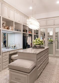 a walk in closet with white cabinets and chandelier