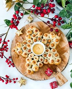 some food is on a wooden plate with holly leaves and red berries around it, the title reads 10 berephapes vor de kerstebbo borel