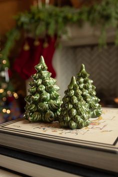 two green christmas trees sitting on top of a book