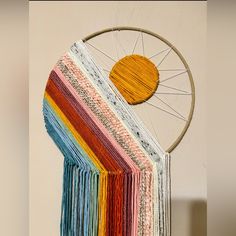 a multicolored piece of yarn hanging from a wall with a sun on it