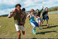 a group of people running across a grass covered field