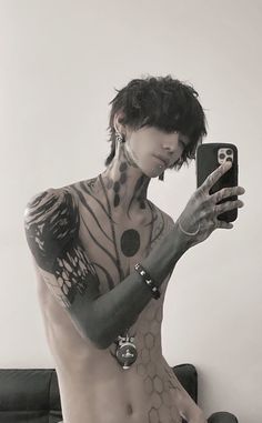 a man with tattoos on his body taking a selfie while holding a cell phone