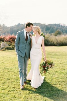 a bride and groom walking in the grass