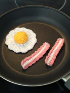 two crocheted bacon and an egg on a frying pan