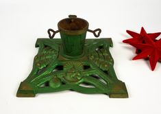 an antique green candle holder next to a red star ornament on a white surface