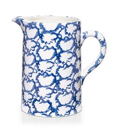 a blue and white pitcher with an intricate design on the bottom, sitting in front of a white background