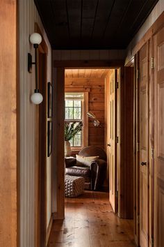 an open door leading to a living room with wood paneling and leather couches