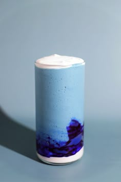 a blue and white vase with purple designs on the bottom is sitting on a gray surface