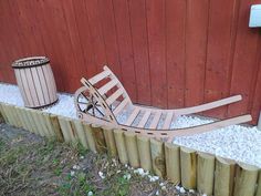 a wooden sled sitting on top of gravel next to a fence