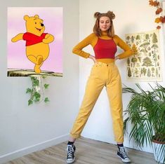 a woman standing in front of a wall with winnie the pooh painting on it