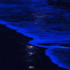 the ocean is blue and black with some waves coming in to shore at night time