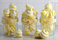 three glass jars filled with yellow and white swirled meringue cookies on top of a counter