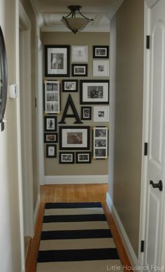 the hallway is decorated with black and white pictures on the wall, along with an area rug