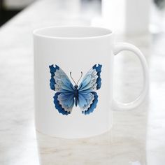 a coffee mug with a blue butterfly on it sitting on a counter top next to another cup