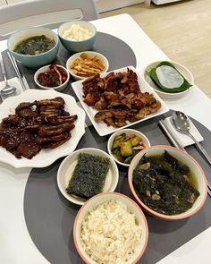 a table topped with plates of food next to bowls of rice and sauces on top of it