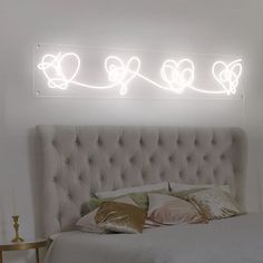 a bed with pillows and lights on the wall above it in a white walled room