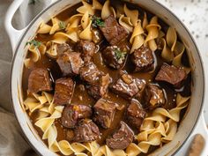 a pot filled with beef and noodles on top of a table