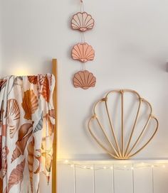 three seashells hanging on the wall above a crib in a room with string lights