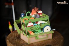 a green box filled with lots of assorted items on top of a wooden table