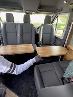 the interior of a van with two tables and seats in front of it, while someone is pointing at them