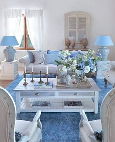 a living room filled with white furniture and blue carpeted flooring next to windows