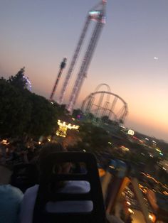 an amusement park at dusk with ferris wheel in the background