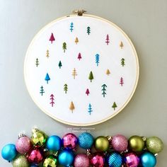 a cross stitch christmas ornament next to an embroidery hoop with ornaments on it